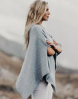 Woman wearing a light gray poncho in a natural setting