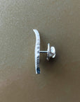 Silver earring with a curved design on a beige background