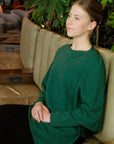 Woman wearing a green leaf poncho sitting on sofa
