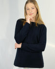 Woman wearing a Ink merino silk sweater with white pants