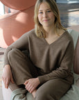 Woman in a brown outfit sitting on a couch in a modern indoor setting