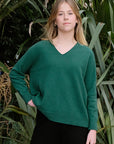 Woman wearing a green sweater standing in front of green plants