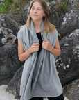 Woman wearing a gray wrap standing among rocks