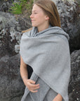 Woman wrapped in a gray stole standing against a rocky background