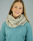 A woman wearing a super-fine merino wool loop scarf in a soft blue color, smiling.