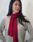 Woman wearing a red scarf and beige sweater against a plain background