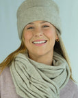 Woman wearing a beige knit hat and scarf against a light blue background