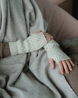 Person wearing white wrist warmer sitting on a beige couch.