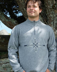 Man wearing a gray sweater with a snowflake design outdoors.