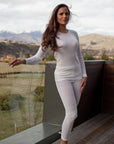 Woman in white outfit standing in a scenic outdoor setting with mountains in the background