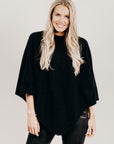 Woman wearing a black poncho and black pants