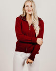 Woman wearing a red jacket with a zipper on a plain background