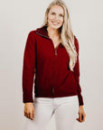 Woman wearing a red zip jacket against a plain background