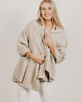 Woman wearing a Lichen Merinosilk Ribbed Wrap with white pants