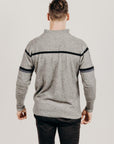 Man wearing a gray sweater with black accents on a plain background