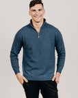 Man wearing a blue sweater with a zipper on a plain background
