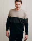 Man wearing a two-tone sweater against a light wooden panel background