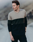 Man wearing a two-tone sweater standing in a mountainous landscape