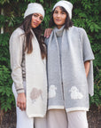 Two women wearing knitted cardigans with animal patterns against a green leafy background