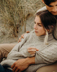 A couple wearing lichen cable turtle neck sweaters