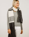 Woman wearing a gray and black striped scarf with a white background