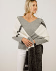 Woman wearing a gray sweater with a scarf against a plain background