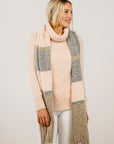 Woman wearing a long, plaid scarf with a neutral background