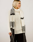 Woman wearing a long, plaid scarf with a plain background