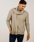 Man wearing a beige sweater and scarf against a plain background