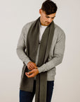 Man wearing a long gray scarf with a plain background