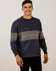 Man wearing a dark blue sweater with a patterned design on a plain background