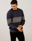 Man wearing a dark blue sweater with a patterned design on a plain background