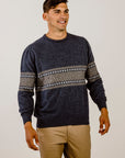 Man wearing a navy sweater with patterned sleeves against a plain background