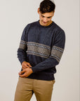 Man wearing a dark blue sweater with a patterned design on a plain background
