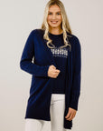 Woman wearing a navy blue cardigan with a white pattern on a plain background