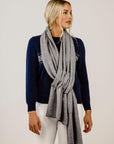 Woman wearing a navy sweater with white pattern and a gray scarf on a plain background