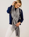 Woman wearing a gray scarf and navy sweater on a white background