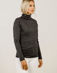 Woman wearing a black and gray striped turtleneck sweater against a plain background