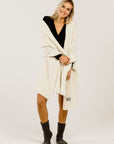 Woman wearing a cream-colored stole over her shoulders and grey socks on a white background