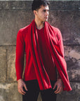 A man wearing a red Cashmere V Neck Sweater, standing next to a wall.