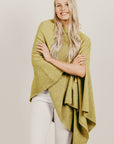 Woman wearing a green poncho against a plain background