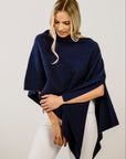 Woman wearing a navy blue poncho against a plain background