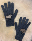 Pair of blue gloves with embroidered sheep design on a fluffy white surface