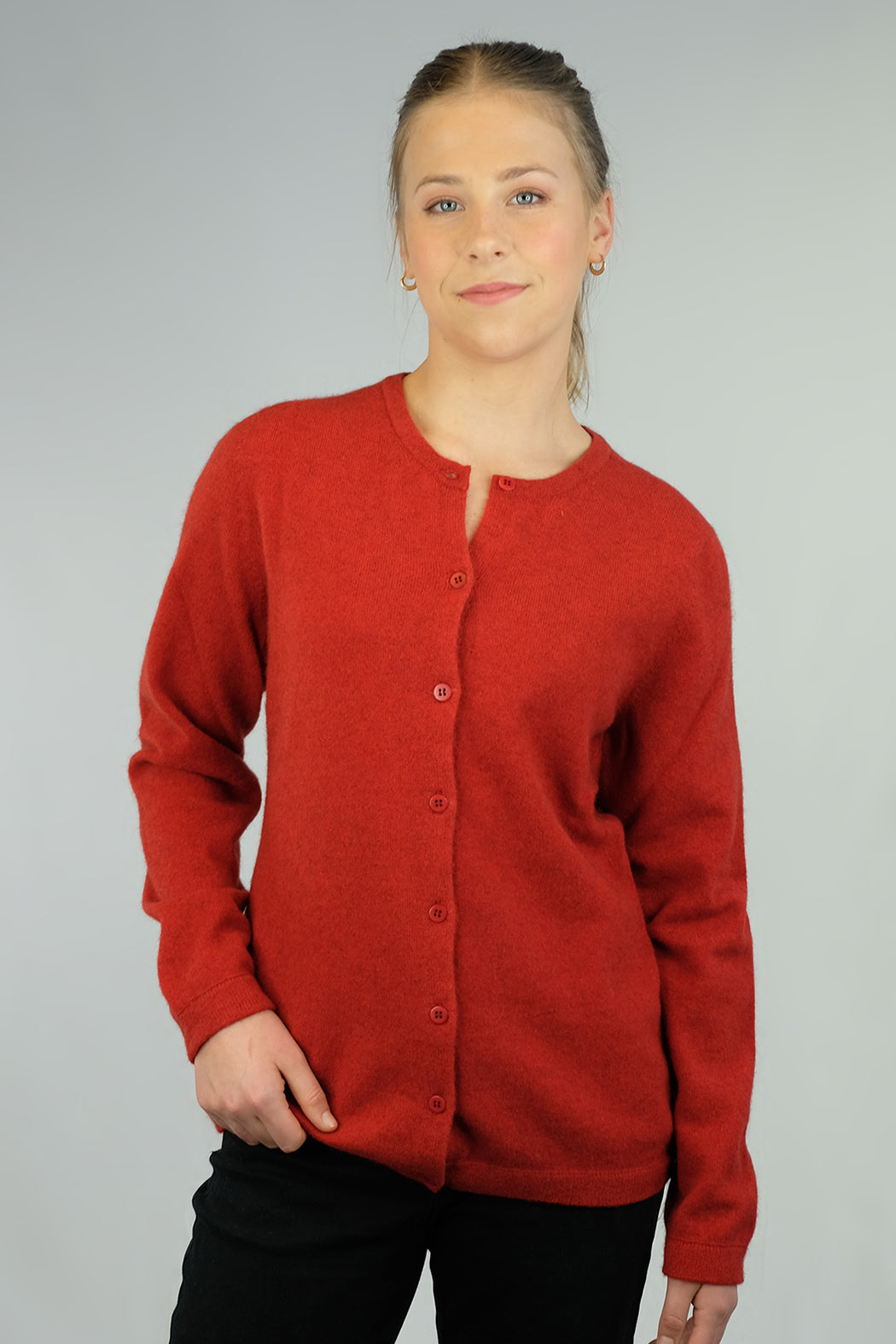 A woman wearing a red Merinosilk plain cardigan with a round neckline and long sleeves.