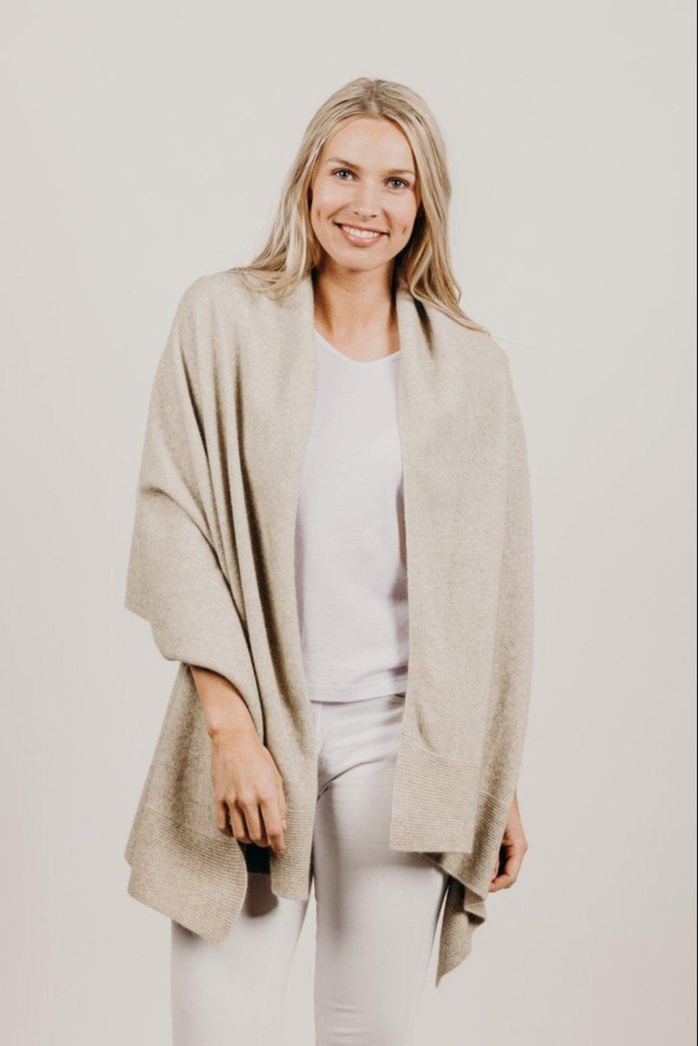 Woman wearing a lichen Merinosilk Ribbed Wrap with white pants
