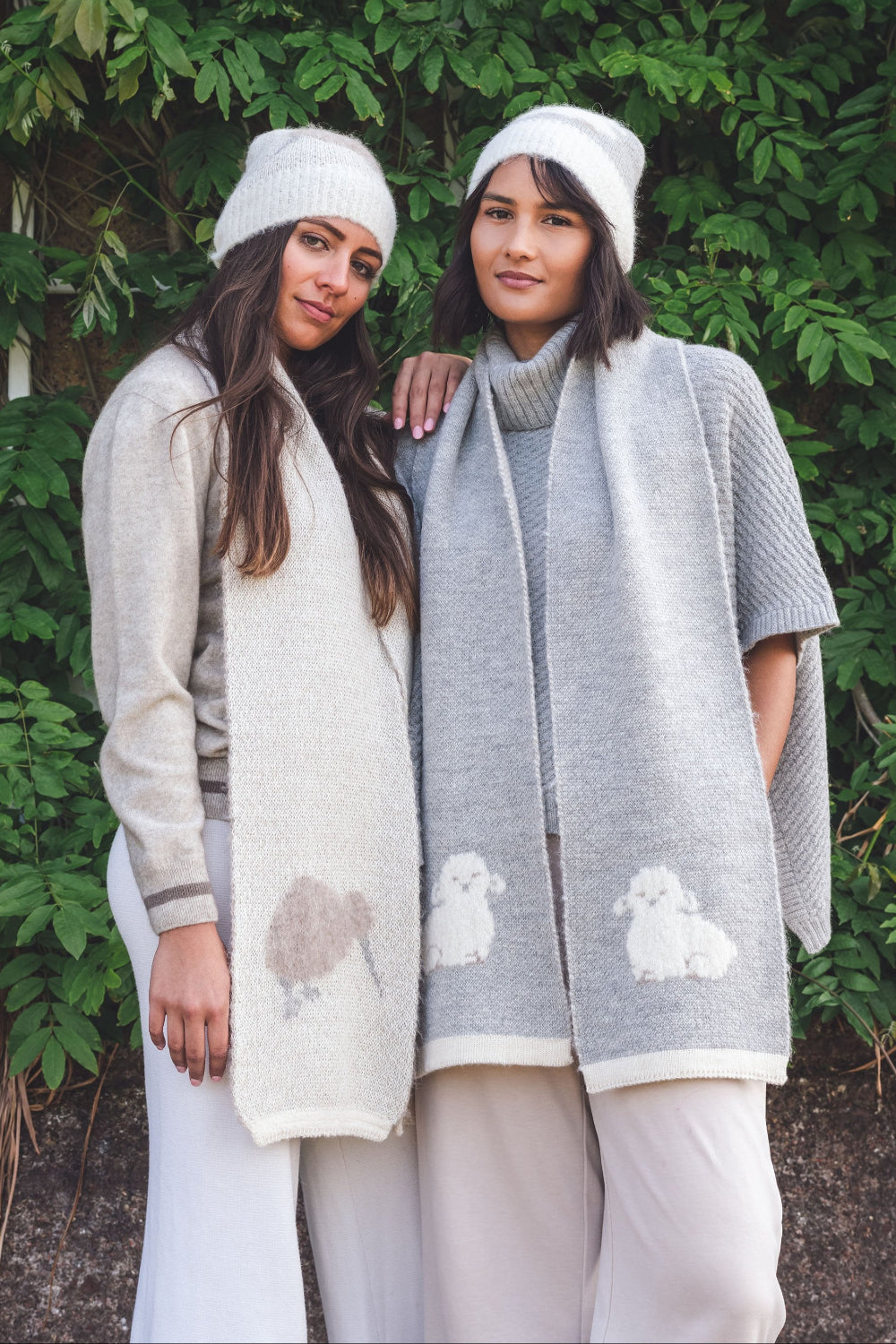Two women wearing knitted cardigans with animal patterns against a green leafy background