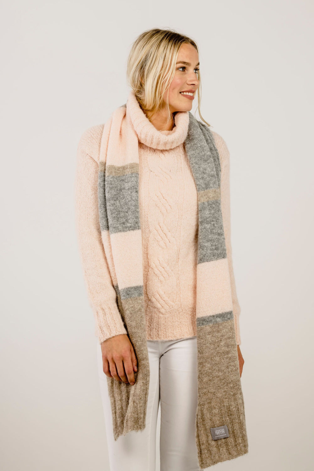 Woman wearing a long, plaid scarf with a neutral background