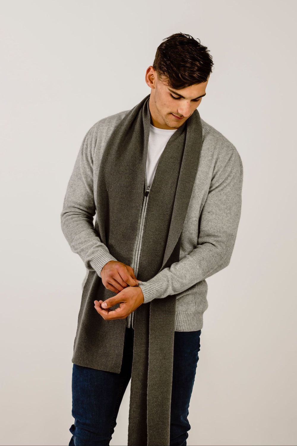 Man wearing a long gray scarf with a plain background